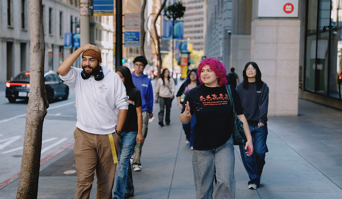 A group of students walk on a street in downtown San Francisco on a sunny day