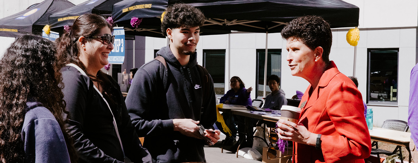 SF State President Lynn Mahoney (right) speaks with a family in front of the newly built West Grove Commons residence hall. Photo by Kevin Perez.