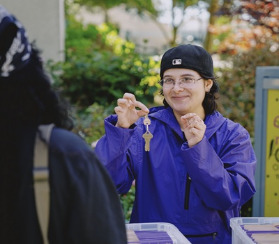 An SFSU welcome worker holds up a room key