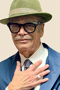 Walter P. Riley places his right hand over his chest while wearing a suit and a fedora