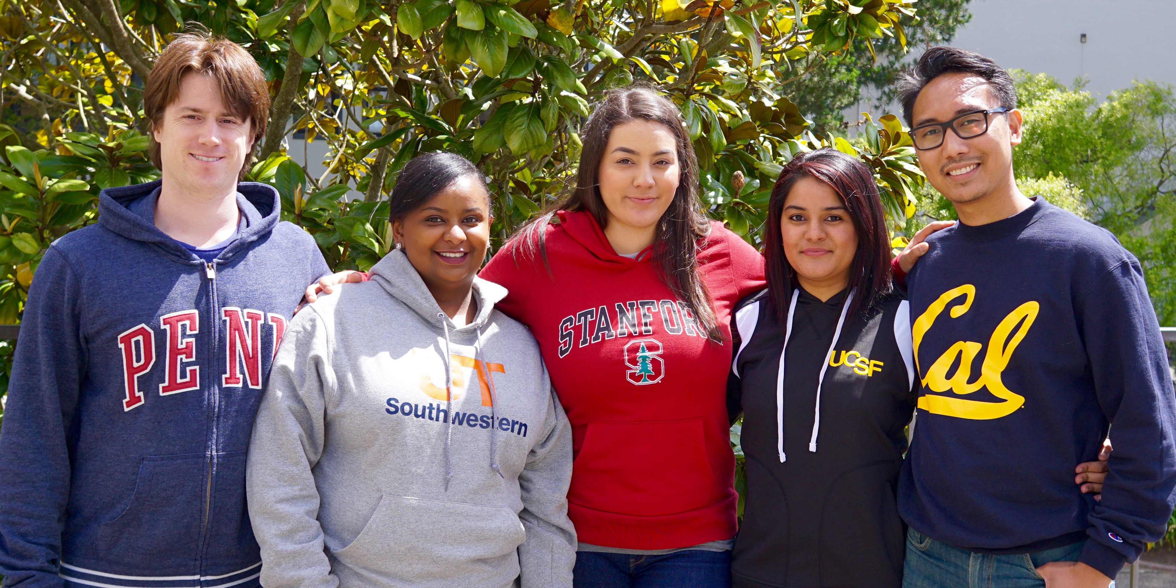 Five students wearing college sweatshirts