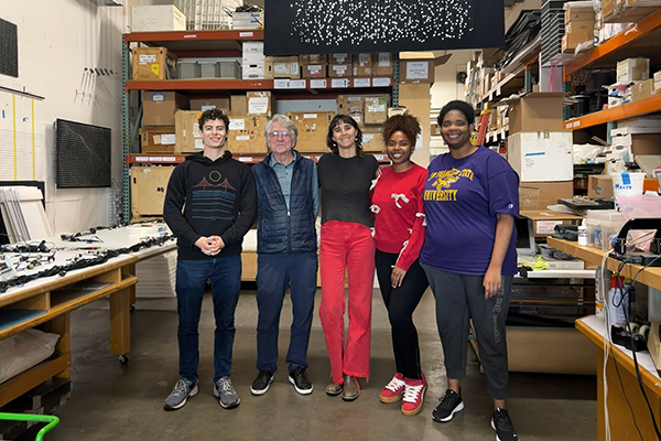 Artists Jim Campbell, Emma Strebel and three students pose for a photo while standing in Campbell's studio