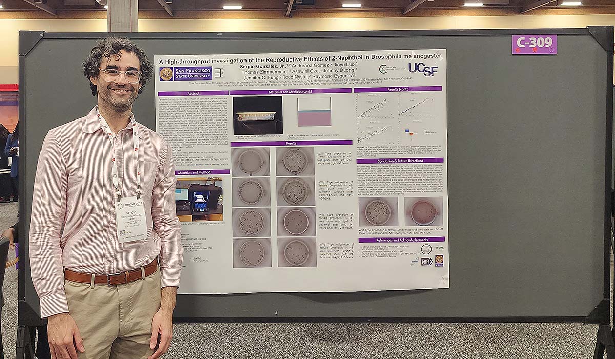 Sergio standing next to his poster at a science conference