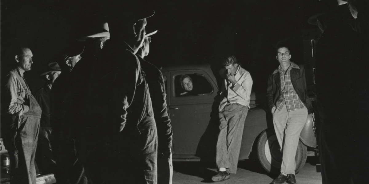 Vintage black and white photo of men hanging out by next to a car