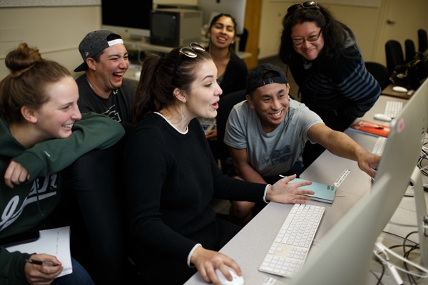 Laughing students look at something on a computer screen