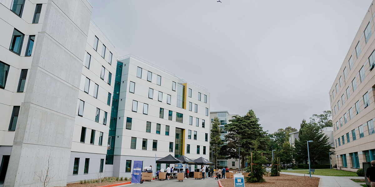 The exterior of West Grove Commons with canopies and tables set up as students and families move in to the residence hall on an overcast day