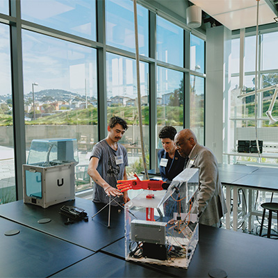 student showing President Mahoney and Willie Brown an engineering project