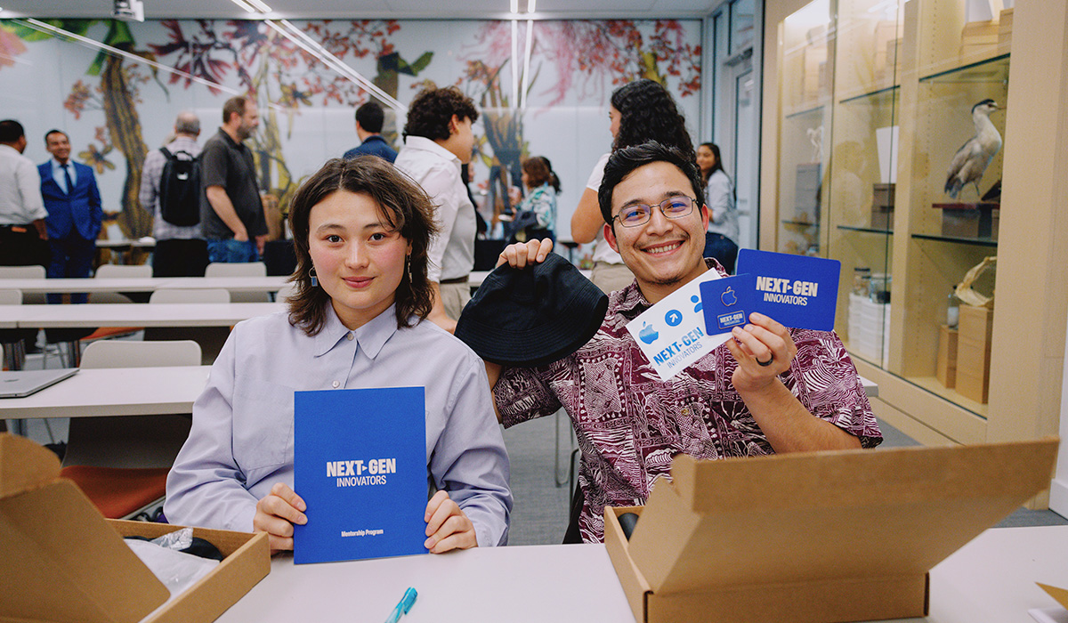 Two students smiling and holding Next-Gen mentorship program booklets
