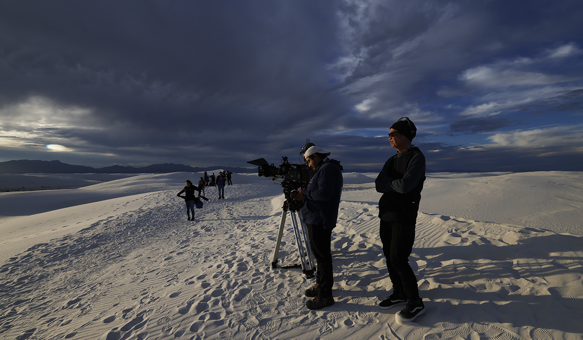 a film stands on sand dunes with camera equipment