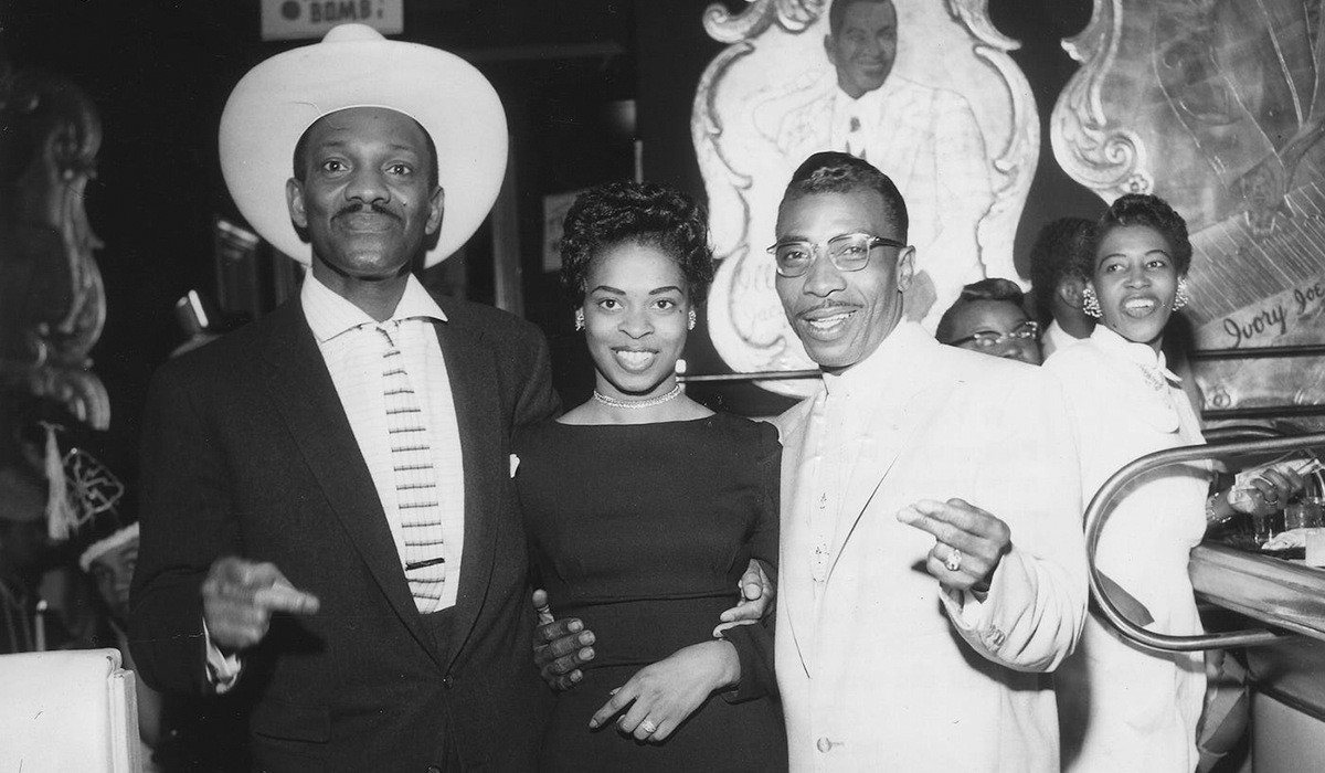 Wesley Johnson, a woman and blues musician T-Bone Walker pose for a picture while standing inside the Texas Playhouse nightclub