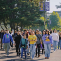 A student tour guide leads future SFSU students and families on a walk through the Quad on a sunny day 