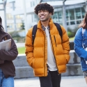 Three students walking in a line on a university campus while they are smiling.