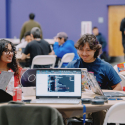 Four students chatting while working on their computers