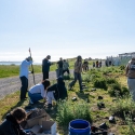 Students gardening outside next to an industrial fence