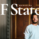 The SF State Magazine spring/summer 2026 issue cover photo of Ryan Marchand standing in front of a wooden door while wearing a gray sweatshirt