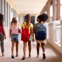 Four girls wearing backpacks walking to school