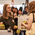 Two students chatting at LCA showcase next to a poster