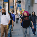 A group of students walk on a street in downtown San Francisco on a sunny day