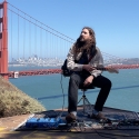 Nate Mercereau seated outdoors in the Marin Headlands holding a guitar