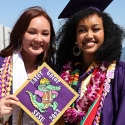 two students holding a decorated cap