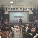 A man on stage in front of an SF Hacks 2025 logo
