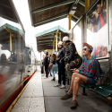 People sit at the SF State/Parkmerced Muni station while a train is stopped