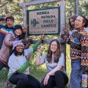 Six students smiling and pointing to the Sierra Nevada Field Campus Sign