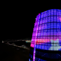 A drone photo of the top of the Salesforce Tower in San Francisco showing colorful SFSU student artwork with the Bay Bridge visible in the background