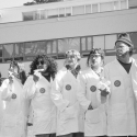 Black and white photo of seven SFSU students in lab coats standing on the Quad