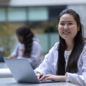 A female student smiles as she works on her laptop
