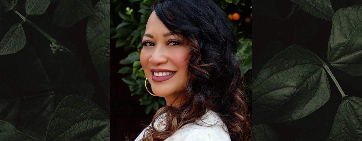 Woman smiling against green foliage