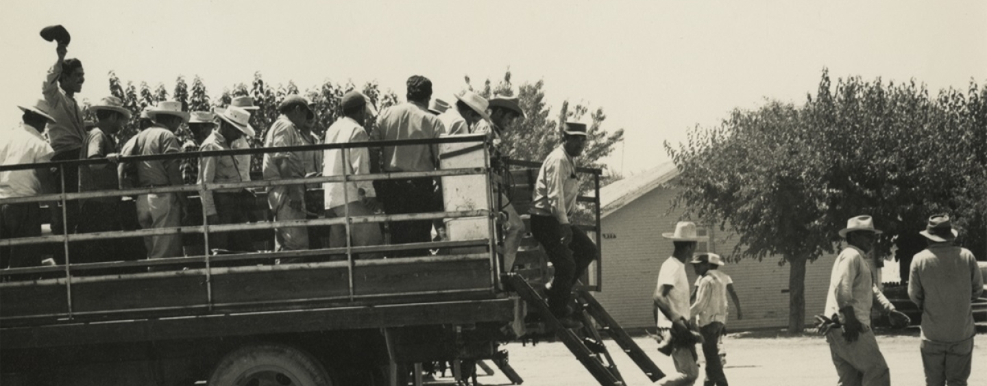 Agricultural workers exit the back of a truck in an archival photo