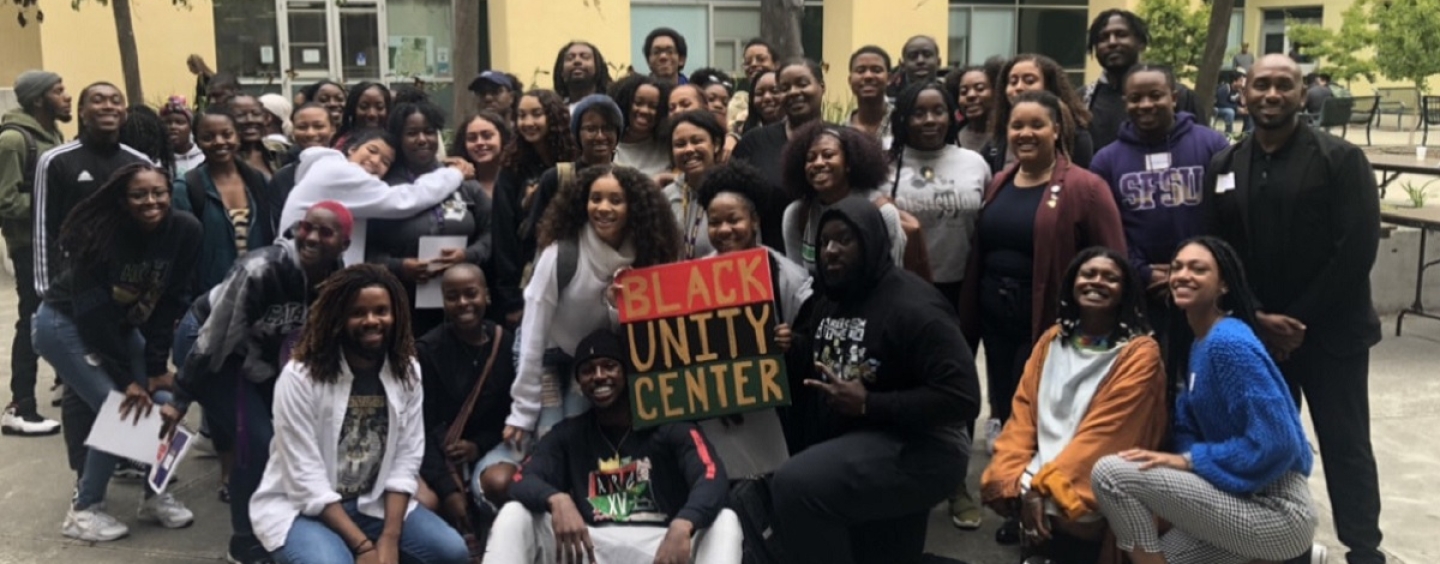 A group of students and staff members gather around a sign saying Black Unity Center