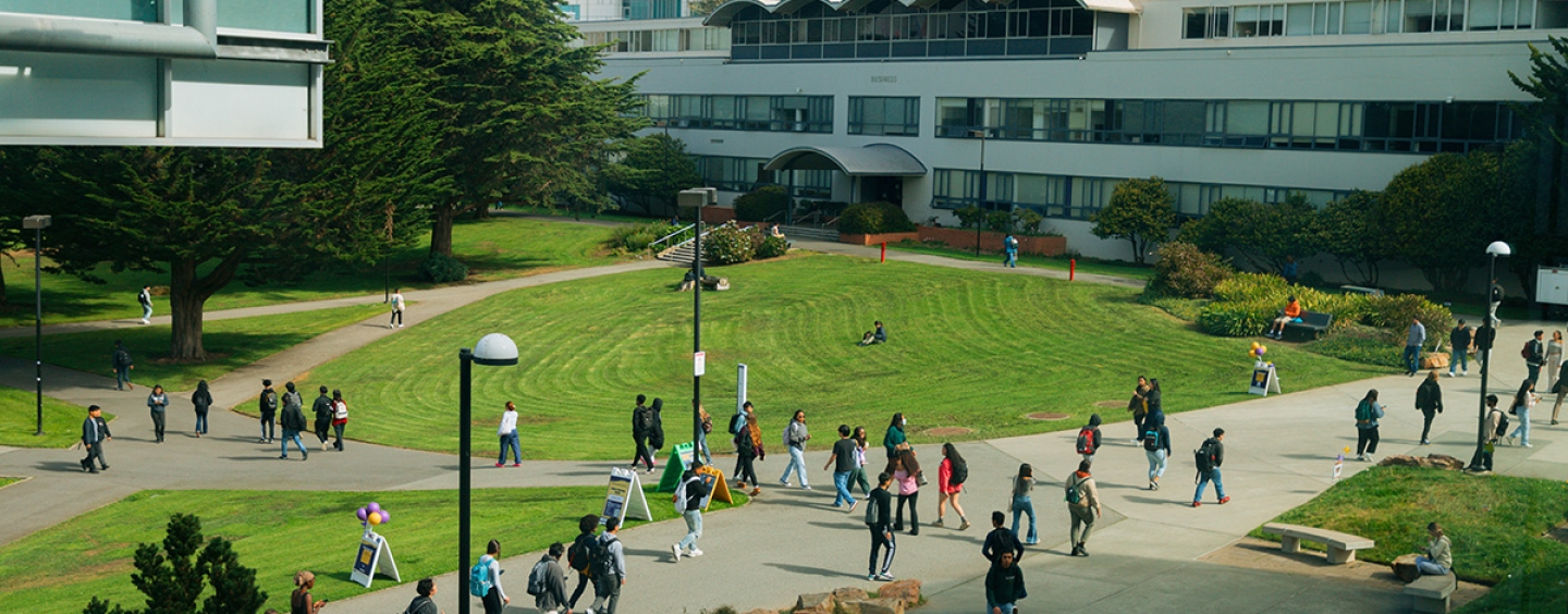 Students and others walk through the SFSU Quad, J. Paul Leonard Library and Business building