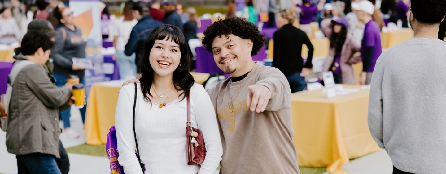 A young woman and young man smile at the camera