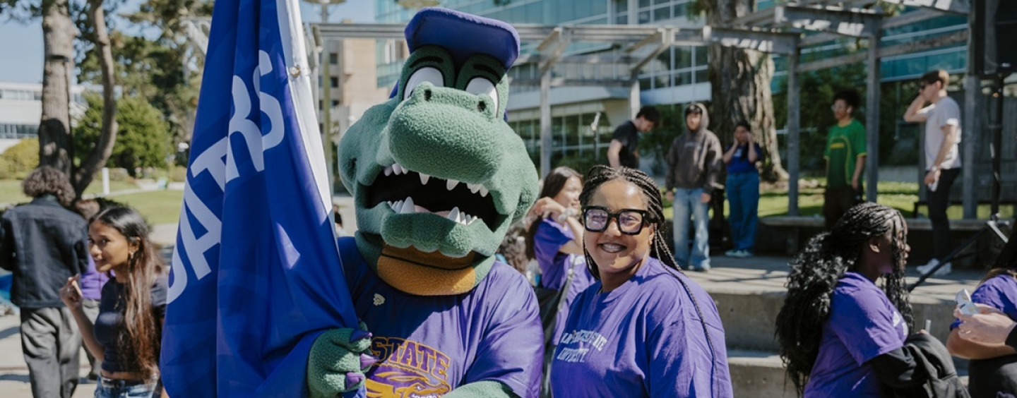 A person in a gator costume stands with a smiling person in a purple t-shirt