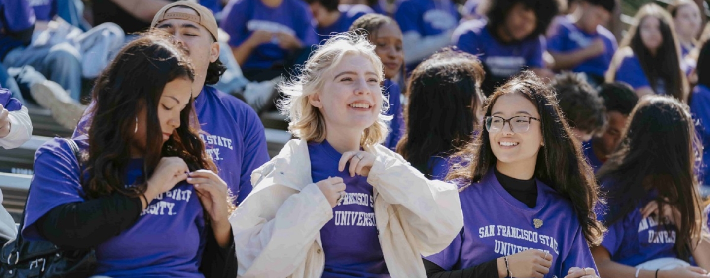 Students in SFSU T-shirts sit together on stadium bleachers