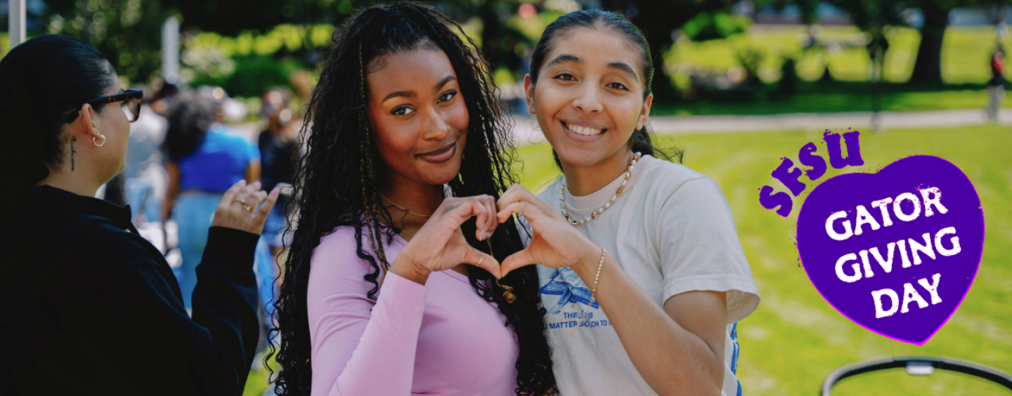 Two students make a heart shape with their hands with the Gator Giving Day logo pasted in the right side of the photo