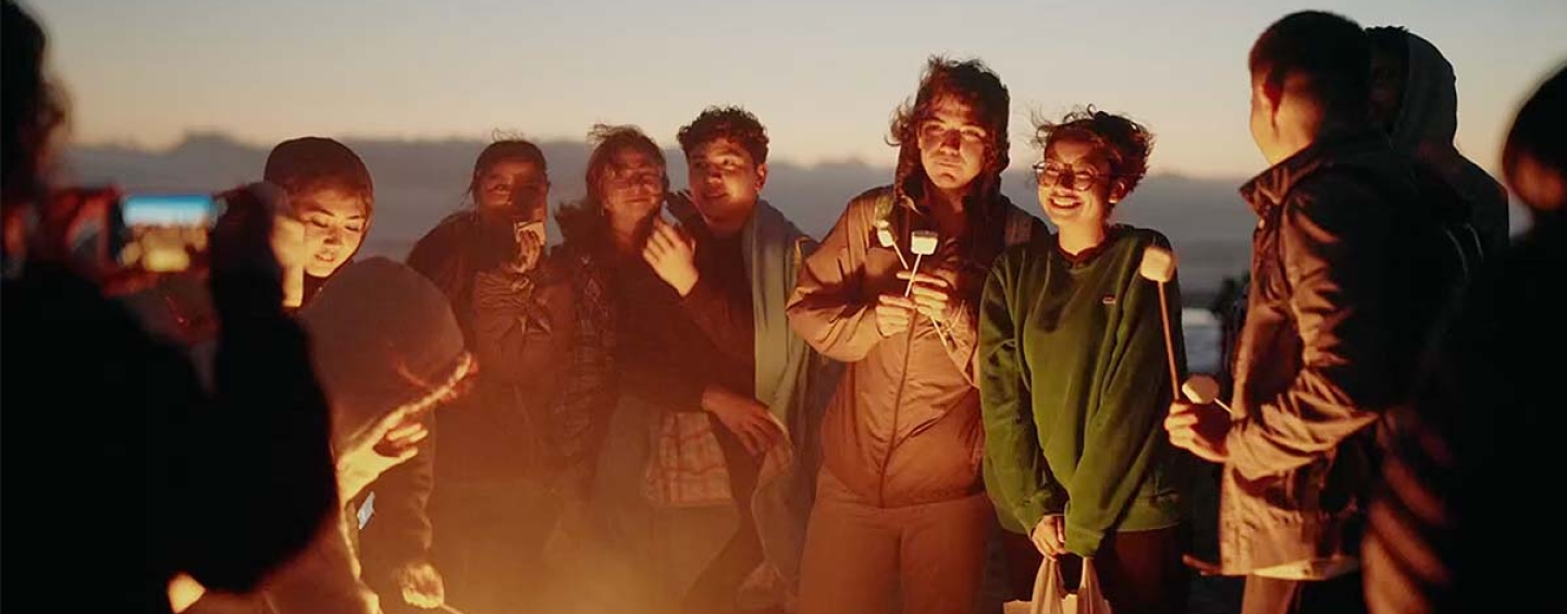 Students with marshmallows on sticks around a bonfire