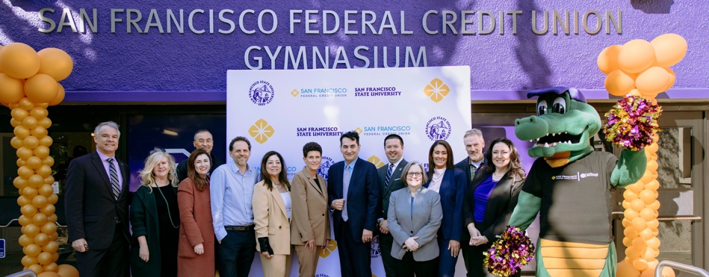 Alli Gator and a group of people in front of the new gym signage
