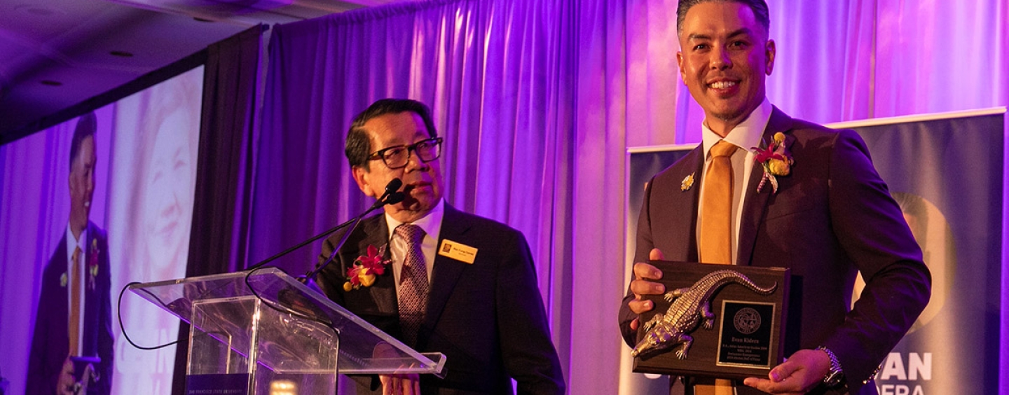Two adults on the stage at the alumni hall of fame event,
