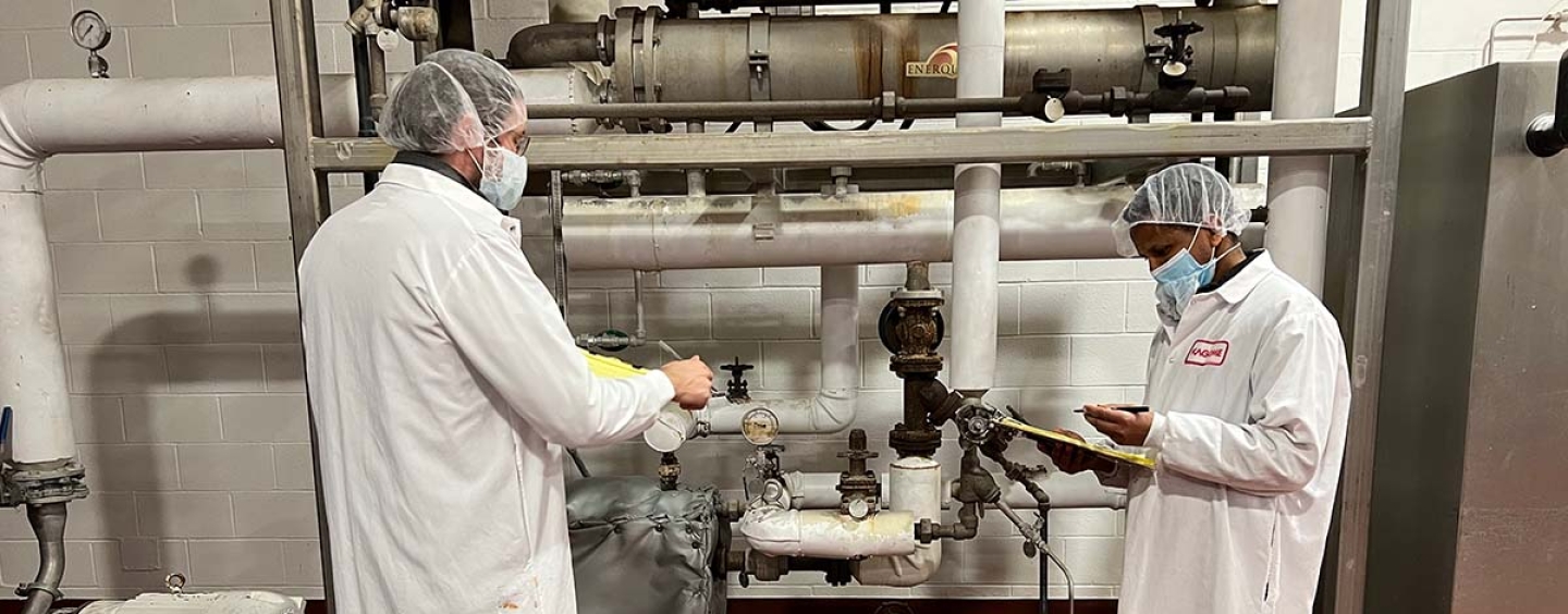 Two students taking notes at a manufacturing plant