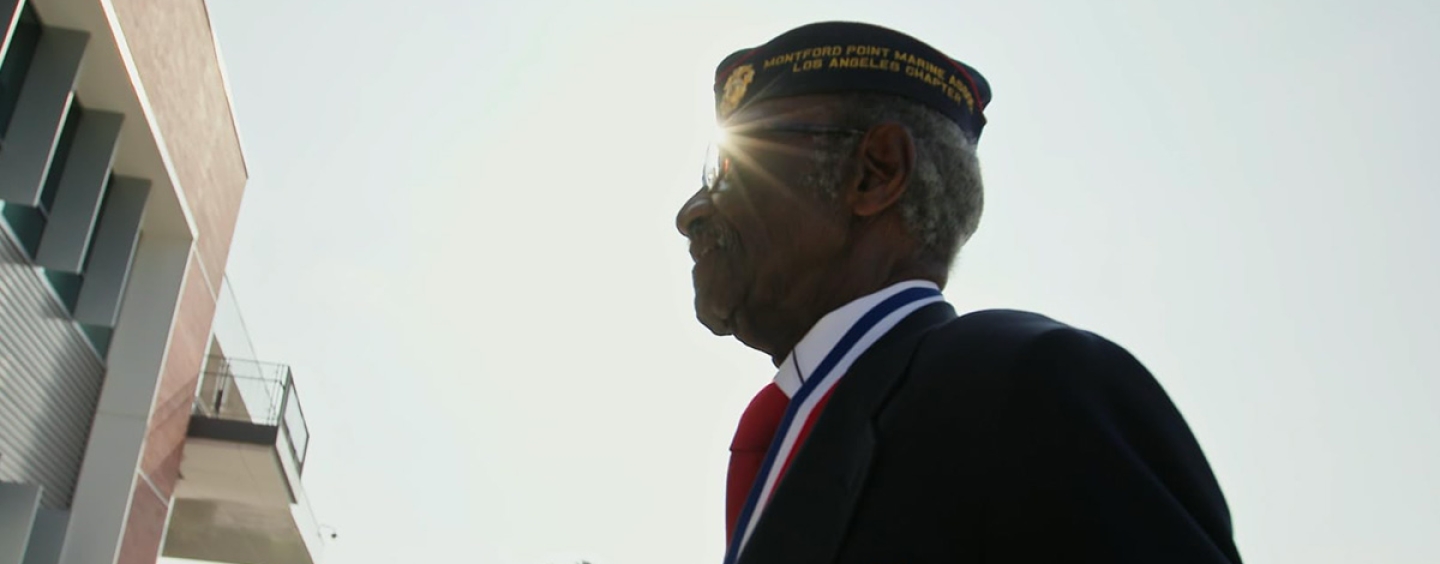 Henry Charles Johnson, a veteran and member of the Montford Point Marines, walks outdoors in uniform on a sunny day