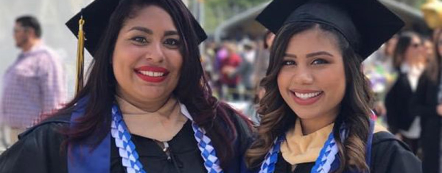 Christina and her sister pose for a photo in commencement regalia 