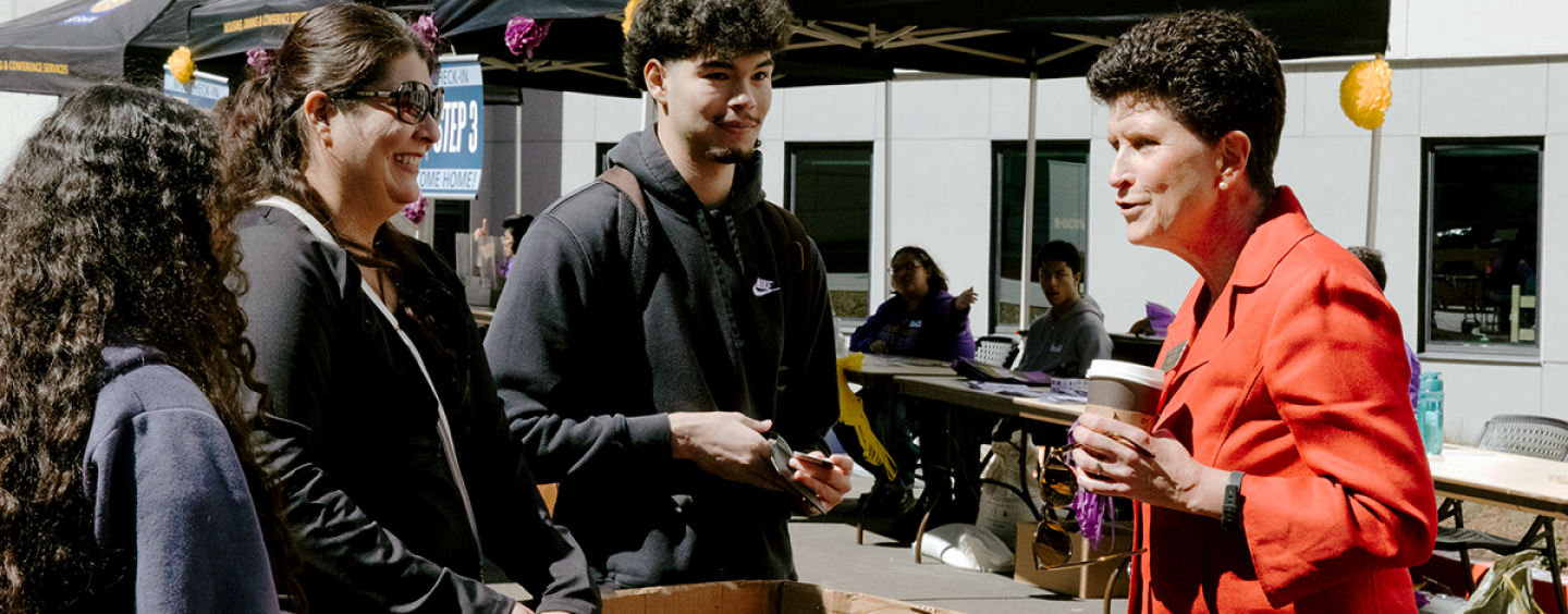 SF State President Lynn Mahoney (right) speaks with a family in front of the newly built West Grove Commons residence hall. Photo by Kevin Perez.