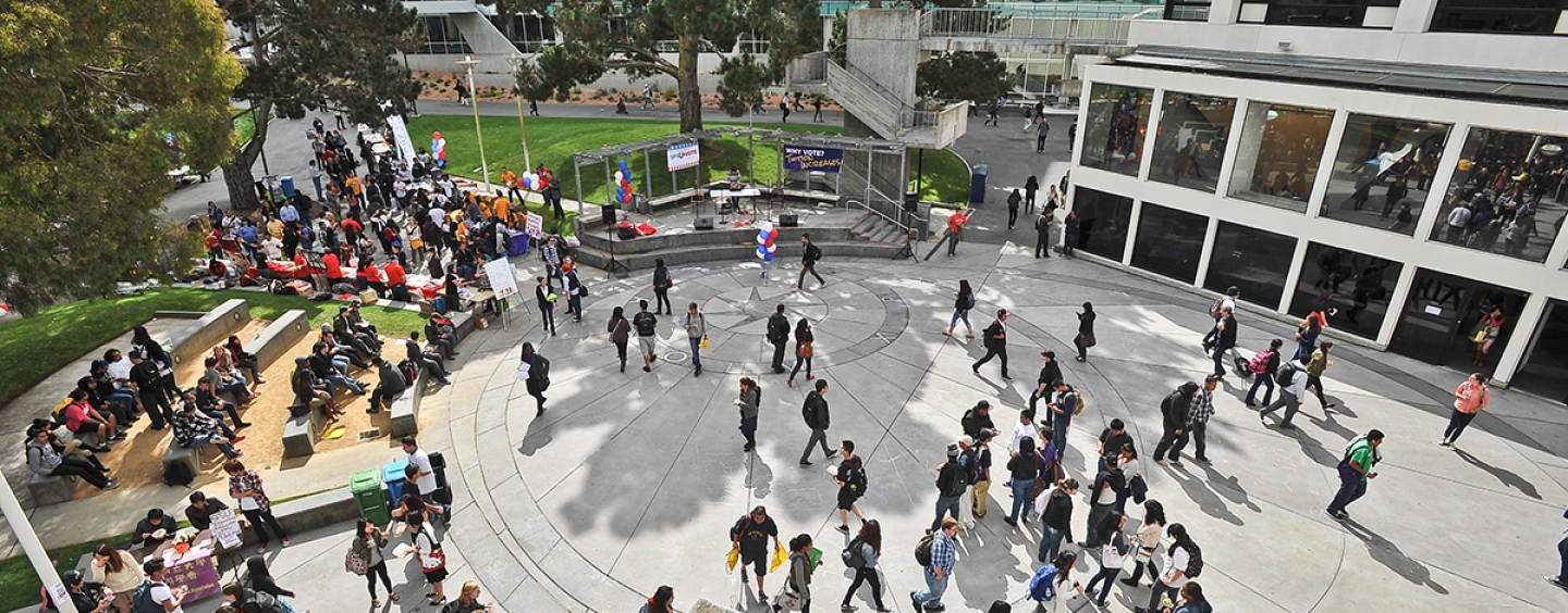 Aerial view of a university campus quad with a crowd of students walking through it.