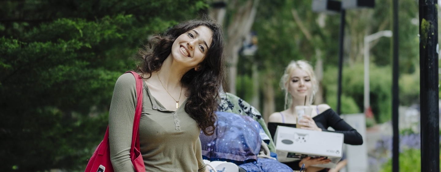 Two smiling female students move their things onto campus