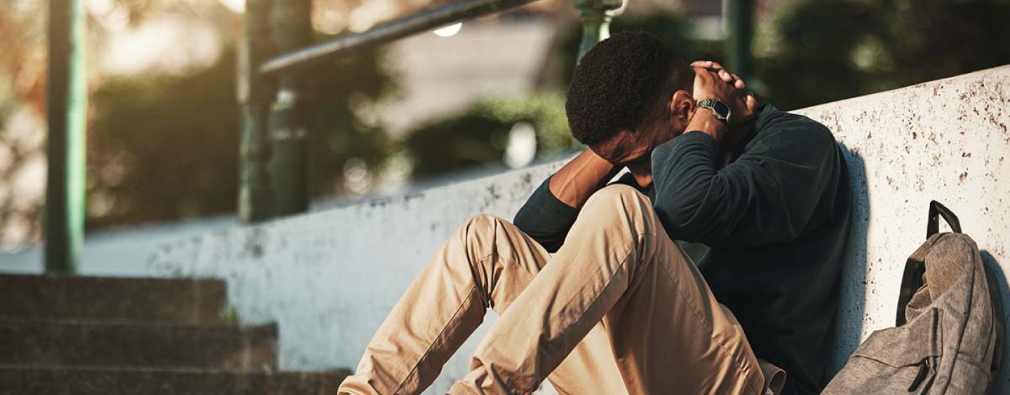 Man sitting on ground holding his head