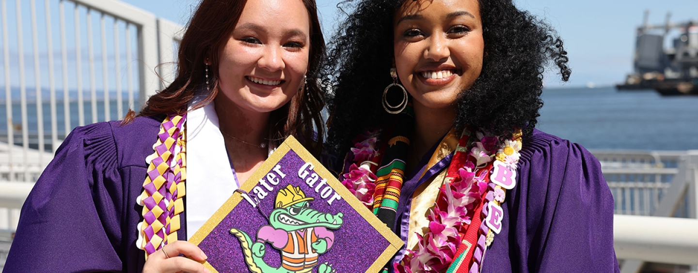 two students holding a decorated cap