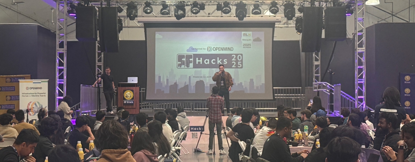 A man on stage in front of an SF Hacks 2025 logo